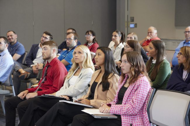 Do it Best interns and staff members listening to a speaker in conference room